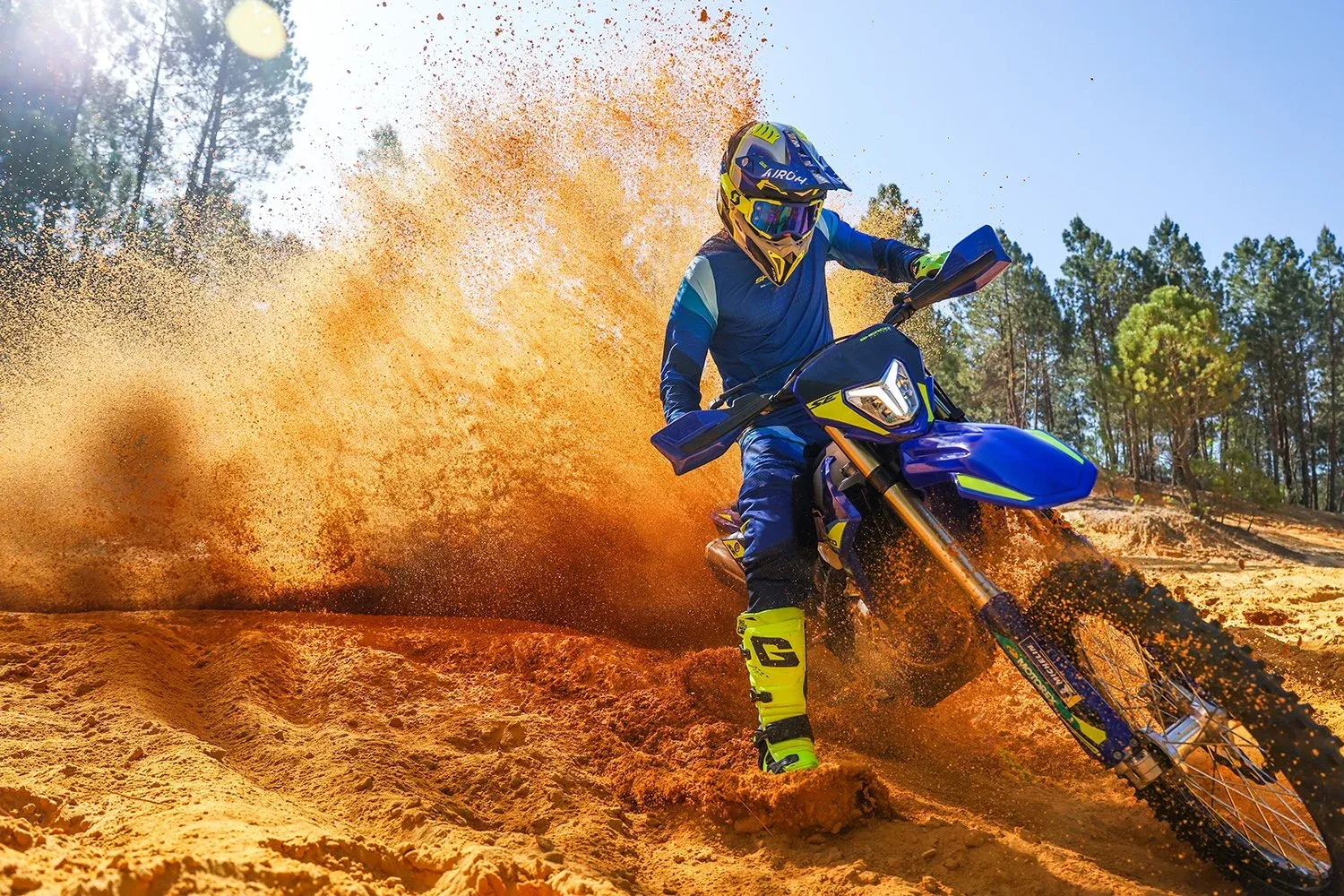 A rider on a 2027 Sherco enduro bike carving through sand, throwing a wall of roost